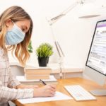 Young business woman working from home, wearing protective mask